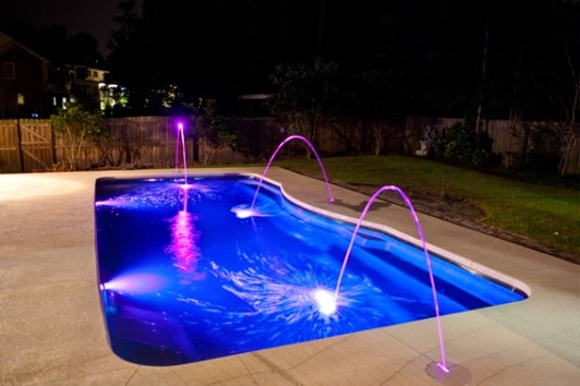 Backyard pool with purple LED-fountain lights. Image source: Patio Pleasures.