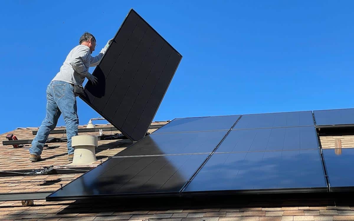 Man on a roof-top installing solar panels at a residence.